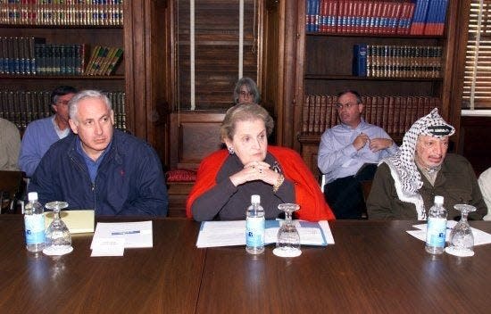 Israeli Prime Minister Benjamin Netanyahu, left at table, U.S. Secretary of State Madeleine Albright, center, and Palestinian National Authority President Yasser Araft, right at table, meet in the libary of Houghton House near Queenstown, Maryland for talks on Middle East peace in October 1998. United States President Bill Clinton played a key role in the negotiations.
