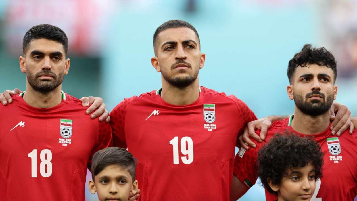 (FromL) Iran's midfielder #18 Ali Karimi, Iran's defender #19 Majid Hosseini and Iran's defender #02 Sadegh Moharrami listen to the national anthem ahead of the Qatar 2022 World Cup Group B football match between England and Iran at the Khalifa International Stadium in Doha on November 21, 2022. (Photo by Fadel Senna / AFP)