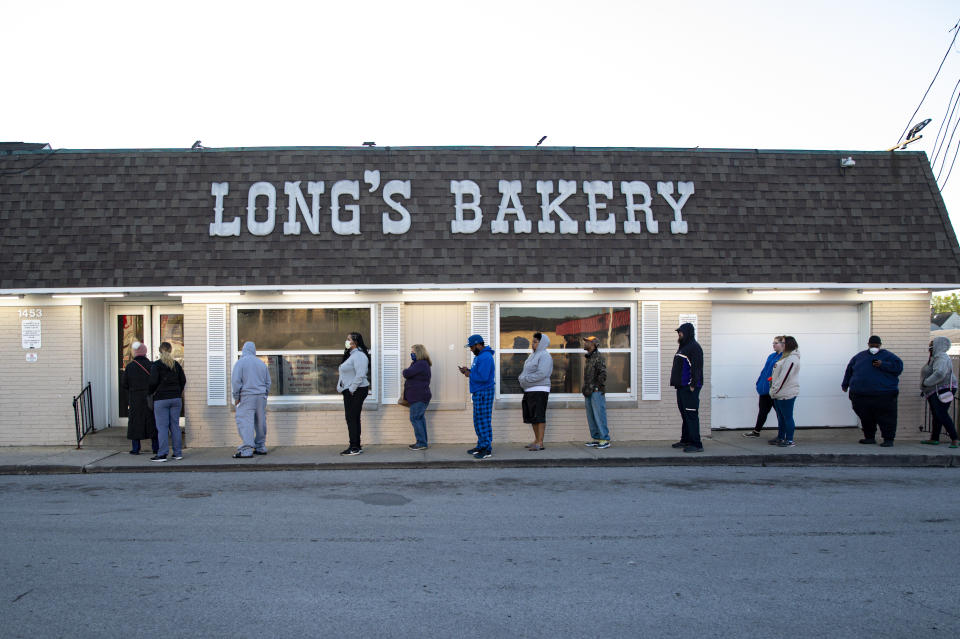 FILE - In this May 1, 2020, file photo, customers wait in line at the Long's Bakery Shop in Indianapolis after the bakery reopened after closing it doors due to COVID-19. The bakery, considered an essential business, reopened as Indianapolis extended the city's stay-at-home order to May 15. Customers waited in the hour-long line to purchase the shop's signature yeast glazed donuts. (AP Photo/Michael Conroy, File)