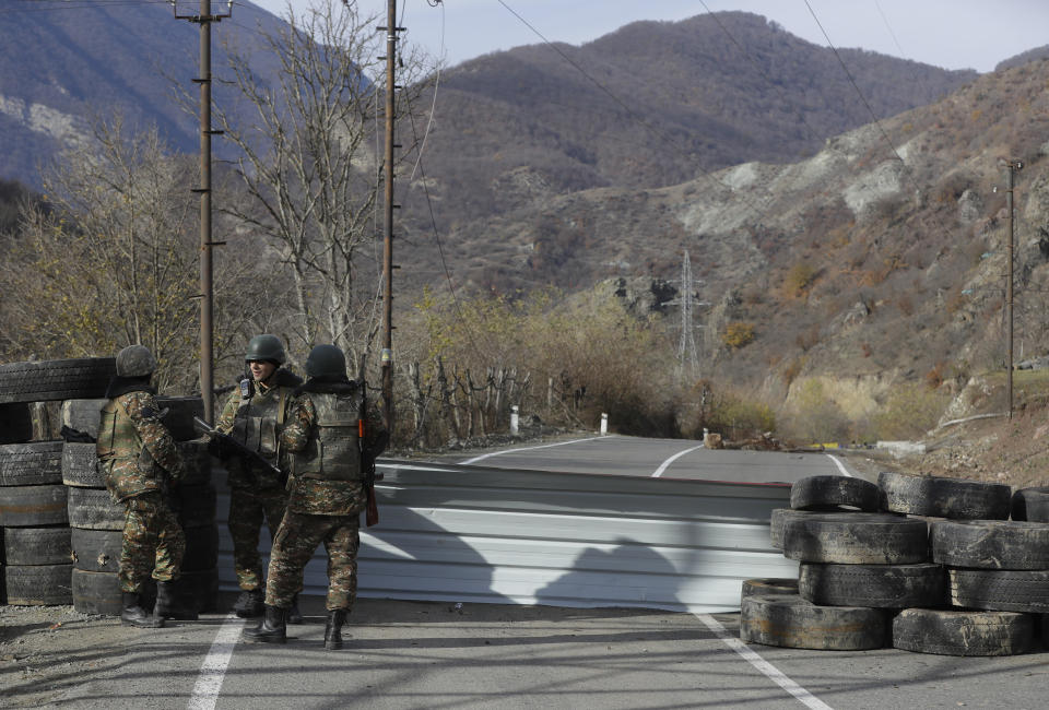 Ethnic Armenian militants stand at a checkpoint near village of Charektar in the separatist region of Nagorno-Karabakh at a new border with Kalbajar district turned over to Azerbaijan, Wednesday, Nov. 25, 2020. The Azerbaijani army has entered the Kalbajar region, one more territory ceded by Armenian forces in a truce that ended deadly fighting over the separatist territory of Nagorno-Karabakh, Azerbaijan's Defense Ministry said Wednesday. The cease-fire, brokered by Russia two weeks ago, stipulated that Armenia hand over control to Azerbaijan of some areas its holds outside Nagorno-Karabakh's borders. (AP Photo/Sergei Grits)