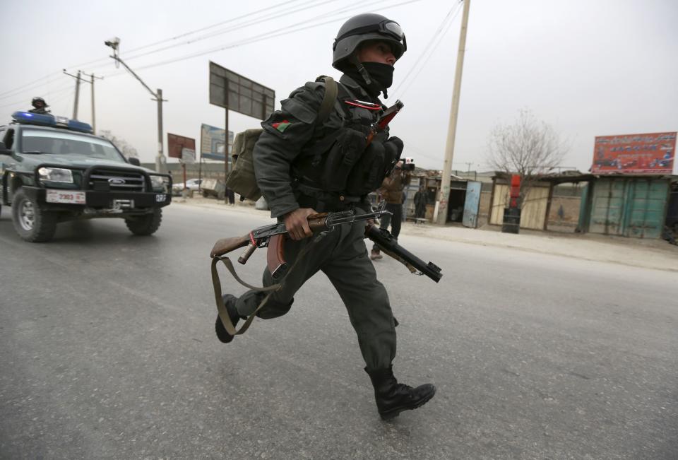 An Afghan policeman runs at the site of a bomb attack in Kabul