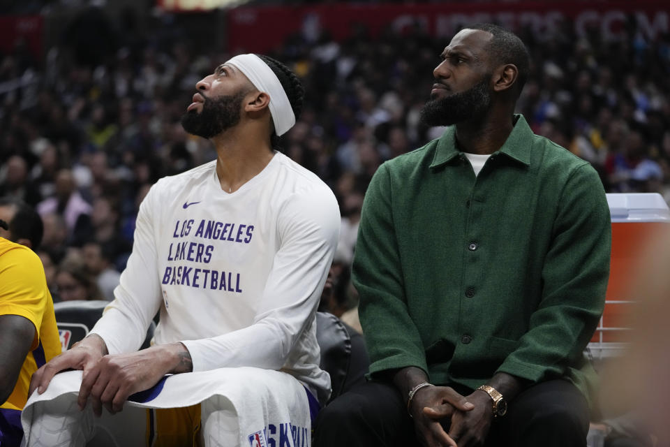 Los Angeles Lakers forward Anthony Davis, left, and LeBron James watch from the bench during the first half of an NBA basketball game against the Los Angeles Clippers in Los Angeles, Tuesday, Jan. 23, 2024. (AP Photo/Ashley Landis)