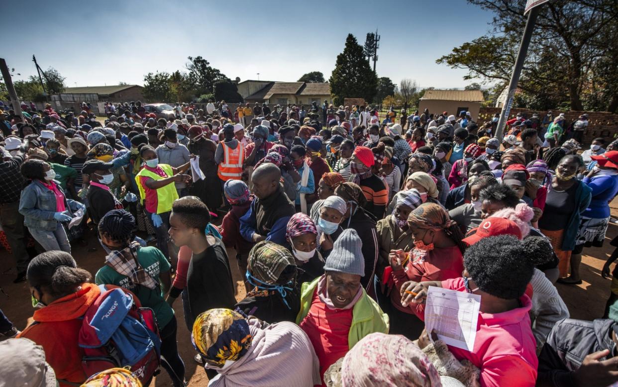 Residents queue to receive parcels of food aid at a distribution point at the Zenzele Counselling Project in Finetown, south of Johannesburg - Bloomberg