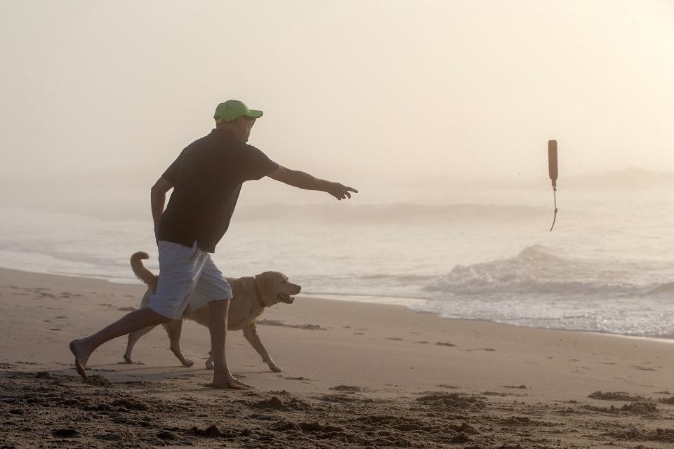 Jim Gannon of New York City throws a toy in the ocean for his dog Picasso at the Asbury Park Beach on July 6, 2023.