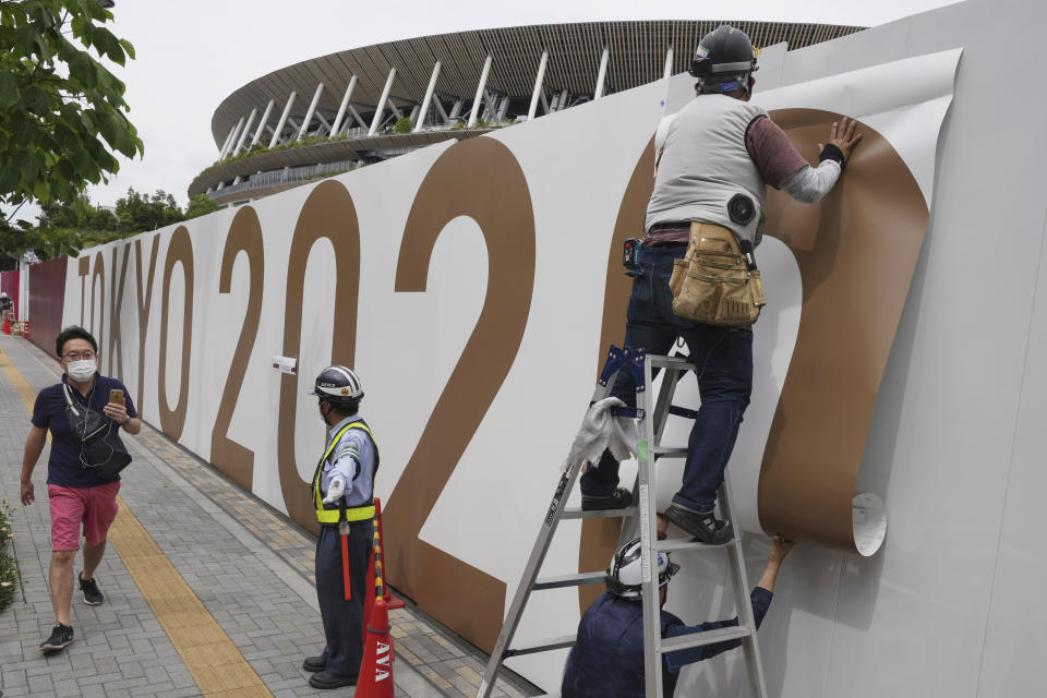 Workers paste the overlay on the wall of the National Stadium, where opening ceremony and many other events are scheduled for the postponed Tokyo 2020 Olympics, Wednesday, June 2, 2021, in Tokyo. Public sentiment in Japan has been generally opposed to holding the Tokyo Olympics and Paralympics. This is partly based of fears the coronavirus will spike as almost 100,000 people — athletes and others — enter for both events. (AP Photo/Eugene Hoshiko, File)