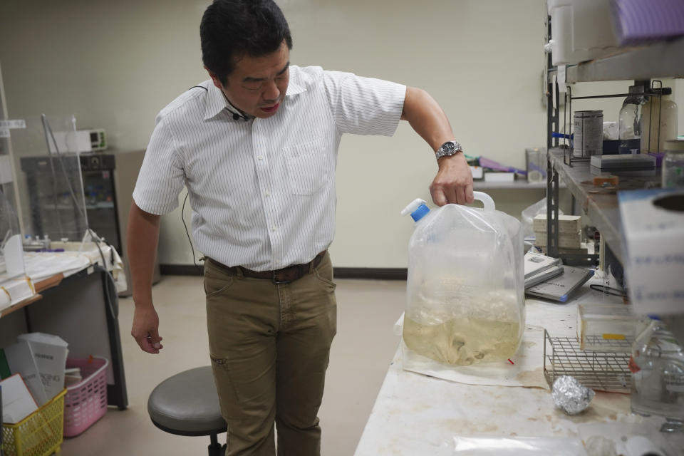 University of Tokyo environmental chemistry professor Katsumi Shozugawa shows the groundwater he collected from a no-go zone just outside of the Fukushima Daiichi nuclear plant complex earlier this year, on Wednesday, July 19, 2023, in Tokyo. Shozugawa said radioactivity of the treated water is so low that once it hits the ocean it will quickly disperse and become almost undetectable, which makes pre-release sampling of the water important for data analysis. (AP Photo/Eugene Hoshiko)