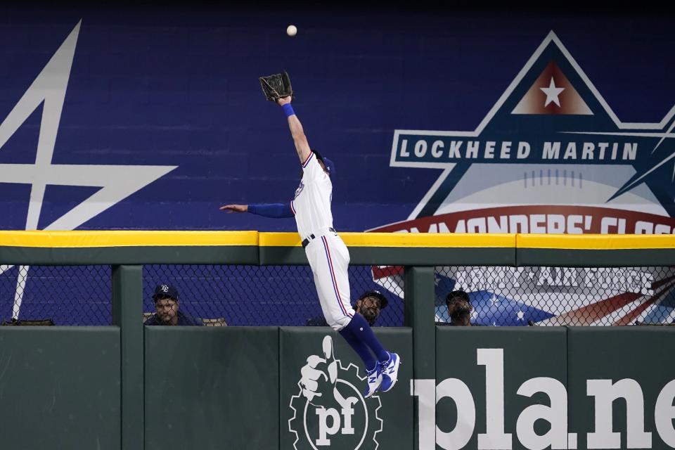 Texas Rangers center fielder Eli White leaps to the top of the wall to catch a flyout by Tampa Bay Rays' Ji-Man Choi in the first inning of a baseball game, Monday, May 30, 2022, in Arlington, Texas. (AP Photo/Tony Gutierrez)