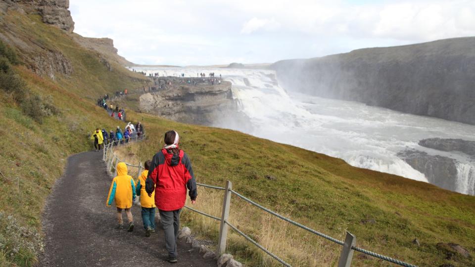 Touristen wandern zum Wasserfall Gullfoss.