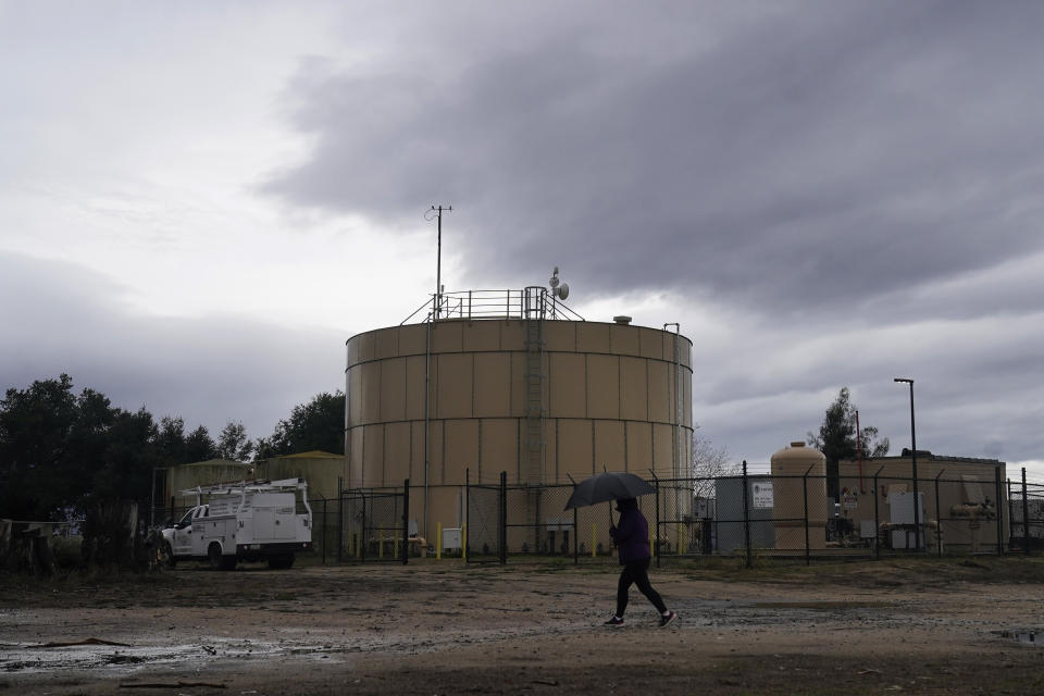 Ileana Miranda walks in front of the new San Jerardo cooperative water tank in Salinas, Calif., Wednesday, Dec. 20, 2023. Some California farming communities have been plagued for years by problems with their drinking water due to nitrates and other contaminants in the groundwater that feeds their wells. (AP Photo/Jeff Chiu)