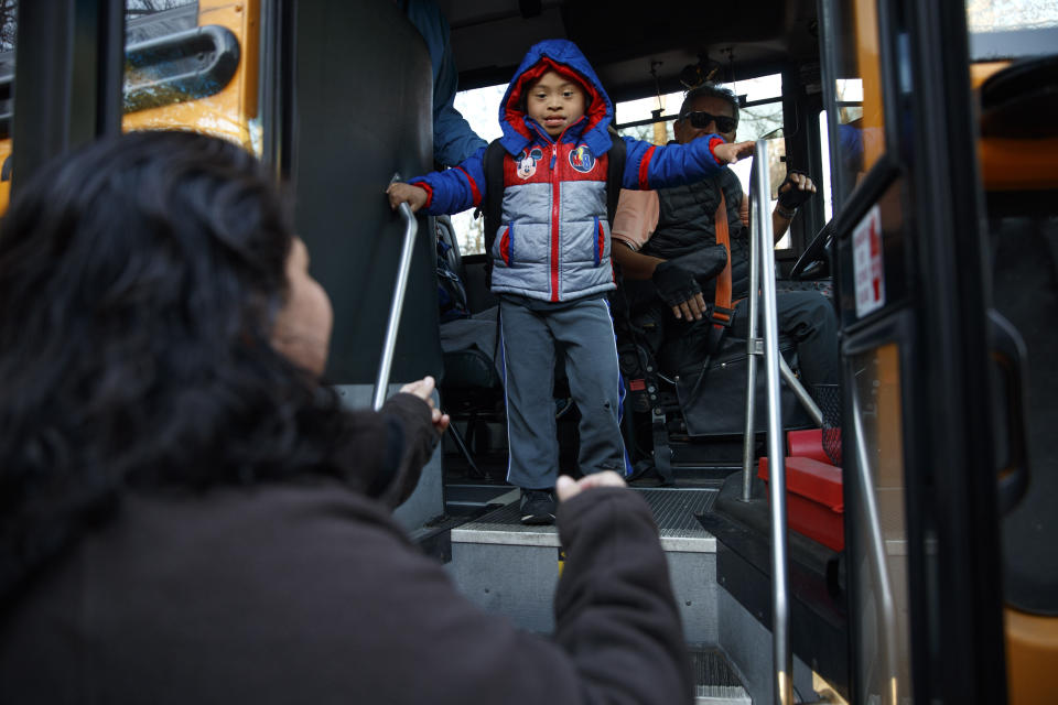 Rosa Gutierrez Lopez, from el Salvador, left, greets her son John, 7, who has Down syndrome, as he gets off the school bus at Cedar Lane Unitarian Universalist Church where the family is living in Bethesda, Md., Thursday, Dec. 5, 2019. Gutierrez Lopez, who a year ago became the first unauthorized immigrant to get refuge inside a religious institution in the Washington area has now been living in sanctuary for a year due to a deportation order. (AP Photo/Jacquelyn Martin)