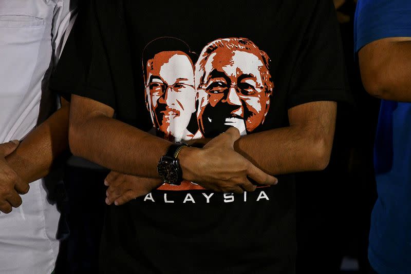 A supporter wearing a t-shirt showing Malaysian politician Anwar Ibrahim and Prime Minister Mahathir Mohamad attends a rally in Kuala Lumpur