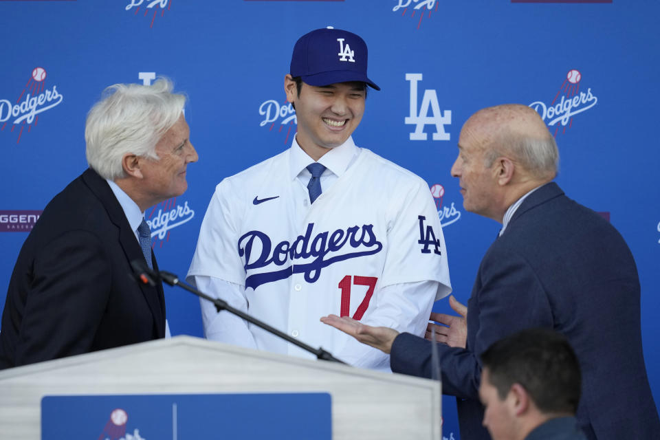 Los Angeles Dodgers' Shohei Ohtani, middle, smiles between owner & chairman Mark Walter, left, and President & CEO Stan Kasten during a baseball news conference at Dodger Stadium Thursday, Dec. 14, 2023, in Los Angeles. (AP Photo/Ashley Landis)