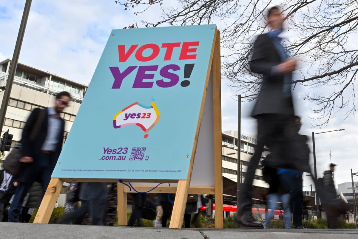 Commuters walk past a vote ‘yes’ stand for the upcoming Voice referendum at the Civic Bus Interchange in Canberra on 30 August  (AAP IMAGE)