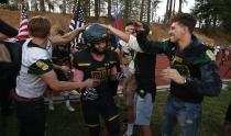 FILE - In this Aug. 23, 2019 file photo, Paradise tight end Jacob Duncan runs through a tunnel of former players during the opening ceremony of their high school football game against Williams, in Paradise, Calif. Paradise, the Northern California high school football team is preparing to play for a championship one year after most of the players and coaches lost their homes to a wildfire that nearly destroyed their town. Paradise High School will face Sutter Union High School on Saturday, Nov. 30 for the Northern Section Division III championship.(AP Photo/Rich Pedroncelli, File)