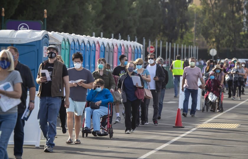 Anaheim, CA - January 13: Orange County active Phase 1A (critical and healthcare workers) residents wait in line to enter large tents at Orange County's first large-scale vaccination site to receive the Moderna COVID-19 vaccine in the Toy Story parking lot at the Disneyland Resort in Anaheim Wednesday, Jan. 13, 2021. Orange County supervisors and Orange County Health Care Agency Director Dr. Clayton Chau held a news conference discussing the county's first Super POD (point-of-dispensing) site for COVID-19 vaccine distribution. The vaccinations are at Tier 1A for people who have reservations on a website. The site is able to handle 7,000 immunizations per day. Their goal is to immunize everyone in Orange County who chooses to do so by July 4th. (Allen J. Schaben / Los Angeles Times)