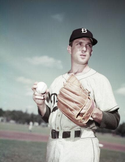 Brooklyn Dodgers pitcher Carl Erskine holds the ball and looks across the field.