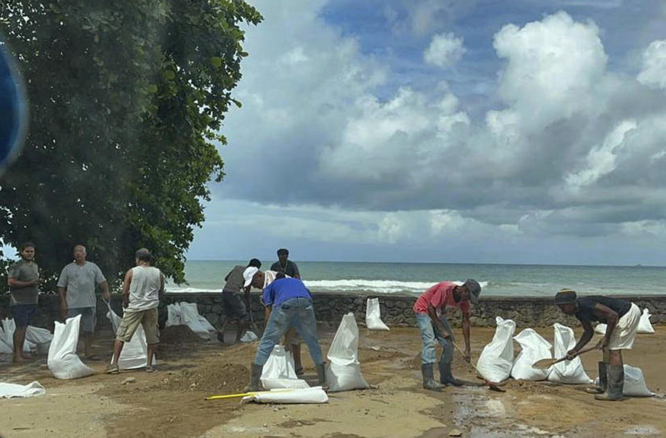 Workers clean the area in the aftermath of a massive explosion at an industrial area on the main island in Mahe, Seychelles, Thursday, Dec. 7, 2023. Authorities in Seychelles declared a state of emergency Thursday after a blast at an explosives store caused “massive damage” in an industrial area also facing flooding amid heavy rainfall, according to the presidency. The blast happened on Wednesday night in the Providence area of Mahe, the largest and most populous island of the Seychelles. (AP Photo/Emilie Chetty)