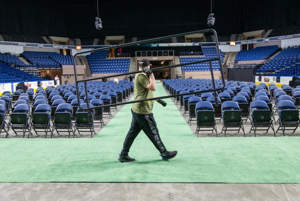 A DCU Center worker carries a section of stage railing Friday as the arena is set up for the first of many graduations over the coming weeks.