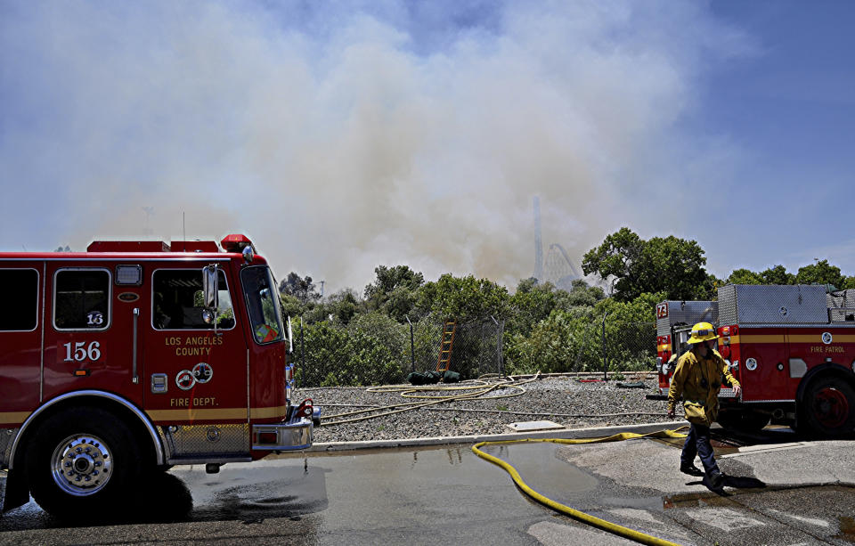Los Angeles County firemen fight a brush fire burning close to Six Flags Magic Mountain and Hurricane Harbor amusement park in Santa Clarita, Calif., Sunday, June 9, 2019. Heavy smoke surrounding Six Flags Magic Mountain and Hurricane Harbor prompted the park to announce an evacuation shortly after noon Sunday north of Los Angeles. But about 40 minutes later, the park said on its Twitter account that fire officials asked guests to stay at the park while they work to contain the blaze. Police closed access roads to the park off Interstate 5. (AP Photo/Rick McClure)