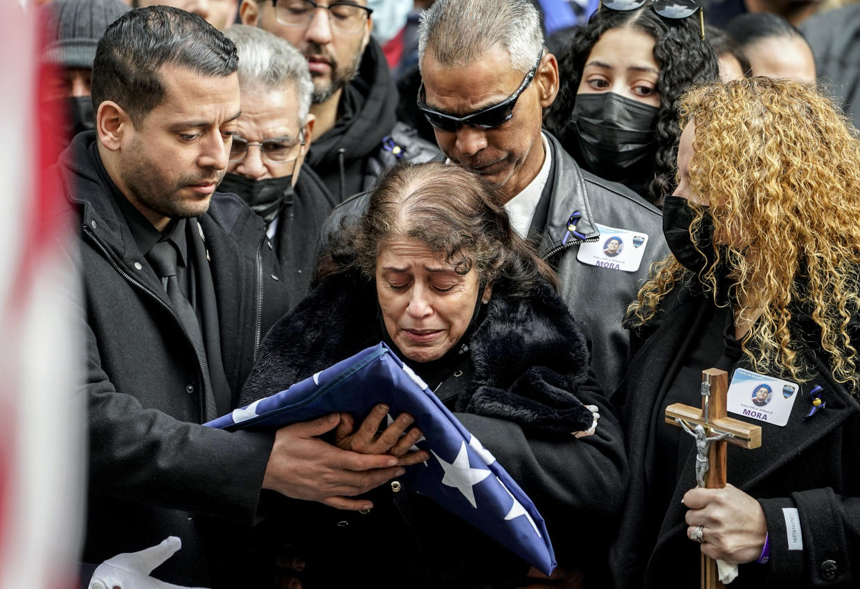 Image: Family members of NYPD Officer Wilbert Mora react after receiving a flag from the honor guard following Mora's funeral at St. Patrick's Cathedral, on Feb. 2, 2022, in New York. (John Minchillo / AP)