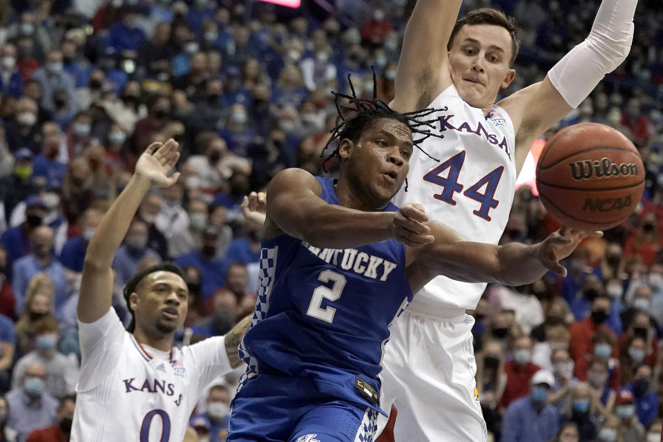 Kentucky guard Sahvir Wheeler (2) passes under pressure from Kansas forward Mitch Lightfoot (44) and guard Bobby Pettiford (0) during the second half of an NCAA college basketball game Saturday, Jan. 29, 2022, in Lawrence, Kan. Kentucky won 80-62. (AP Photo/Charlie Riedel)