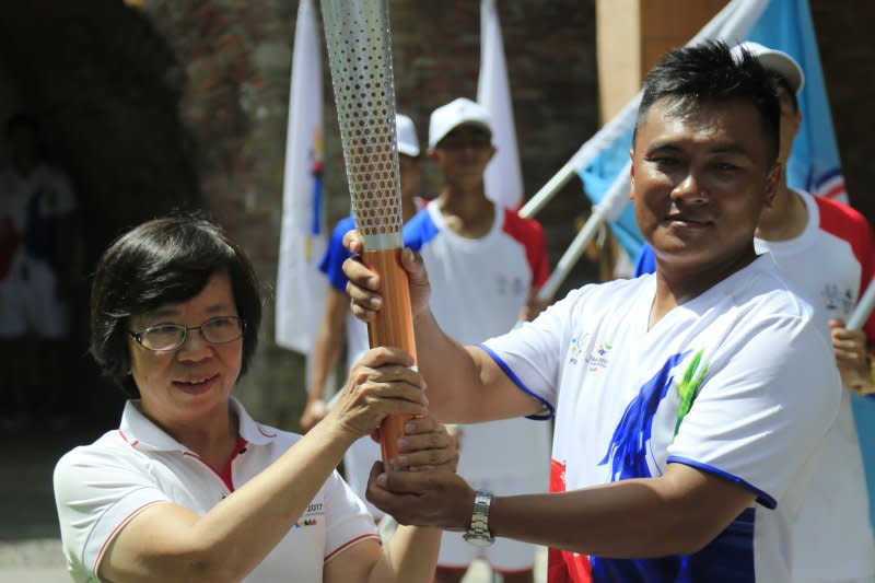 世大運執行長蘇麗瓊（左）將聖火傳遞給選手。（屏東縣政府提供）