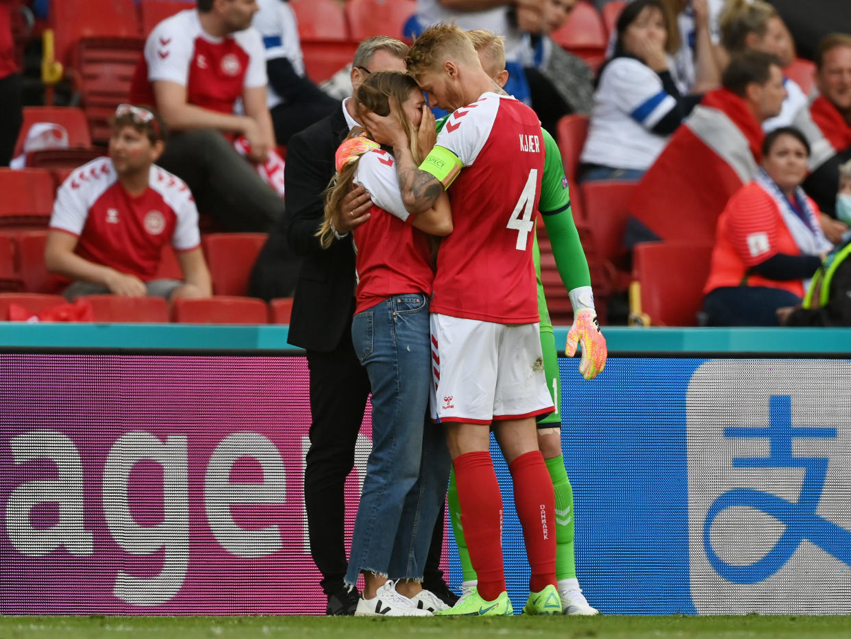 Sabrina Kvist Jensen, Christian Eriksen's girlfriend, is consoled by Denmark defender and captain Simon Kjaer as Eriksen receives medical treatment. (Photo by Stuart Franklin/Getty Images)