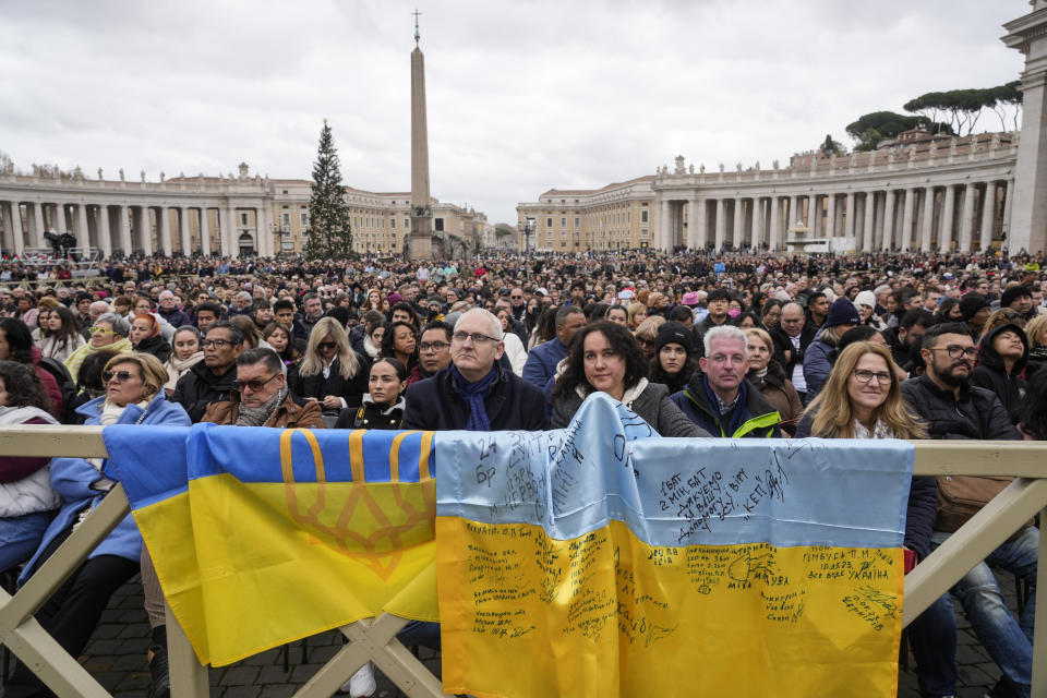 Faithful stand by Ukrainian flags as they listen to Pope Francis delivering the Urbi et Orbi (Latin for 'to the city and to the world' ) Christmas' day blessing from the main balcony of St. Peter's Basilica at the Vatican, Monday Dec. 25, 2023. (AP Photo/Gregorio Borgia)