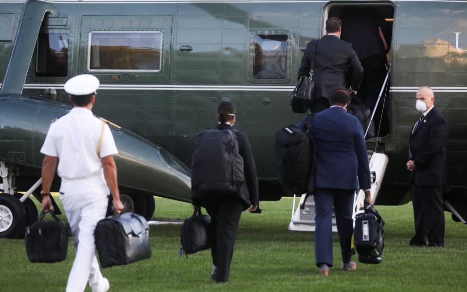 White House aides, including the military aide carrying the nuclear launch codes known as "the nuclear football," follow U.S. President Donald Trump as he boards the Marine One - REUTERS