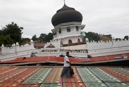 A Muslim man walks across a carpet before Friday prayers at Jami Quba mosque which collapsed during this week's earthquake in Pidie Jaya, Aceh province, Indonesia December 9, 2016. REUTERS/Darren Whiteside