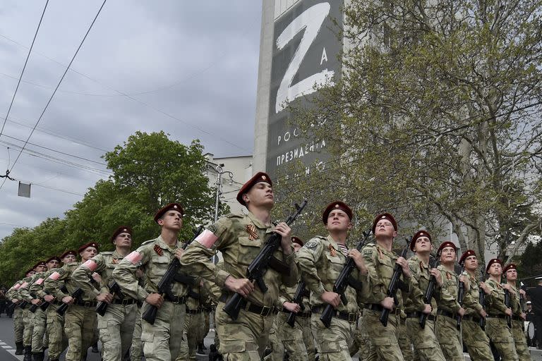 Elementos de la Guardia Nacional de Rusia marchan por una calle mientras en un edificio al fondo se ve la imagen de la letra Z, que se ha convertido en un s&#xed;mbolo del ej&#xe9;rcito de Rusia, el jueves 5 de mayo de 2022, en Sebastopol, Crimea. (AP Foto)