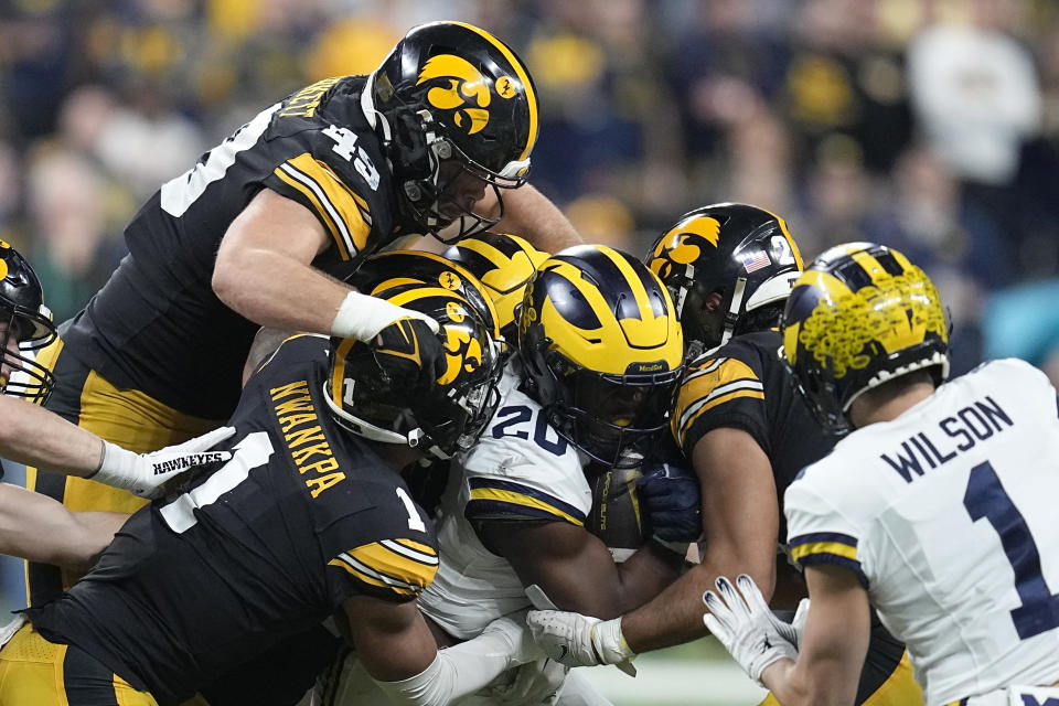 Michigan running back Kalel Mullings (20) is tackled by Iowa defenders during the second half of the Big Ten championship NCAA college football game, Saturday, Dec. 2, 2023, in Indianapolis. (AP Photo/Darron Cummings)
