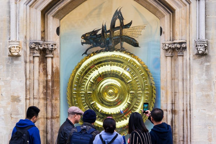 <span class="caption">Tourists looking at John Taylor’s Corpus Clock, which features an insect named Chronophage – ‘Time Eater’.</span> <span class="attribution"><a class="link " href="https://www.shutterstock.com/image-photo/cambridgeukseptember-32017tourists-looking-john-taylors-corpus-719930587?src=2-3FX_M1Am9iJL5GvA0FWw-1-1" rel="nofollow noopener" target="_blank" data-ylk="slk:Pajor Pawel / Shutterstock.com;elm:context_link;itc:0;sec:content-canvas">Pajor Pawel / Shutterstock.com</a></span>