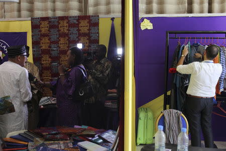 Nigerien designer Alphadi (L) gives an interview while another designer arranges his outfits on a rack during the Festi'Bazin trade show in Bamako, Mali, October 15, 2015. REUTERS/Joe Penney