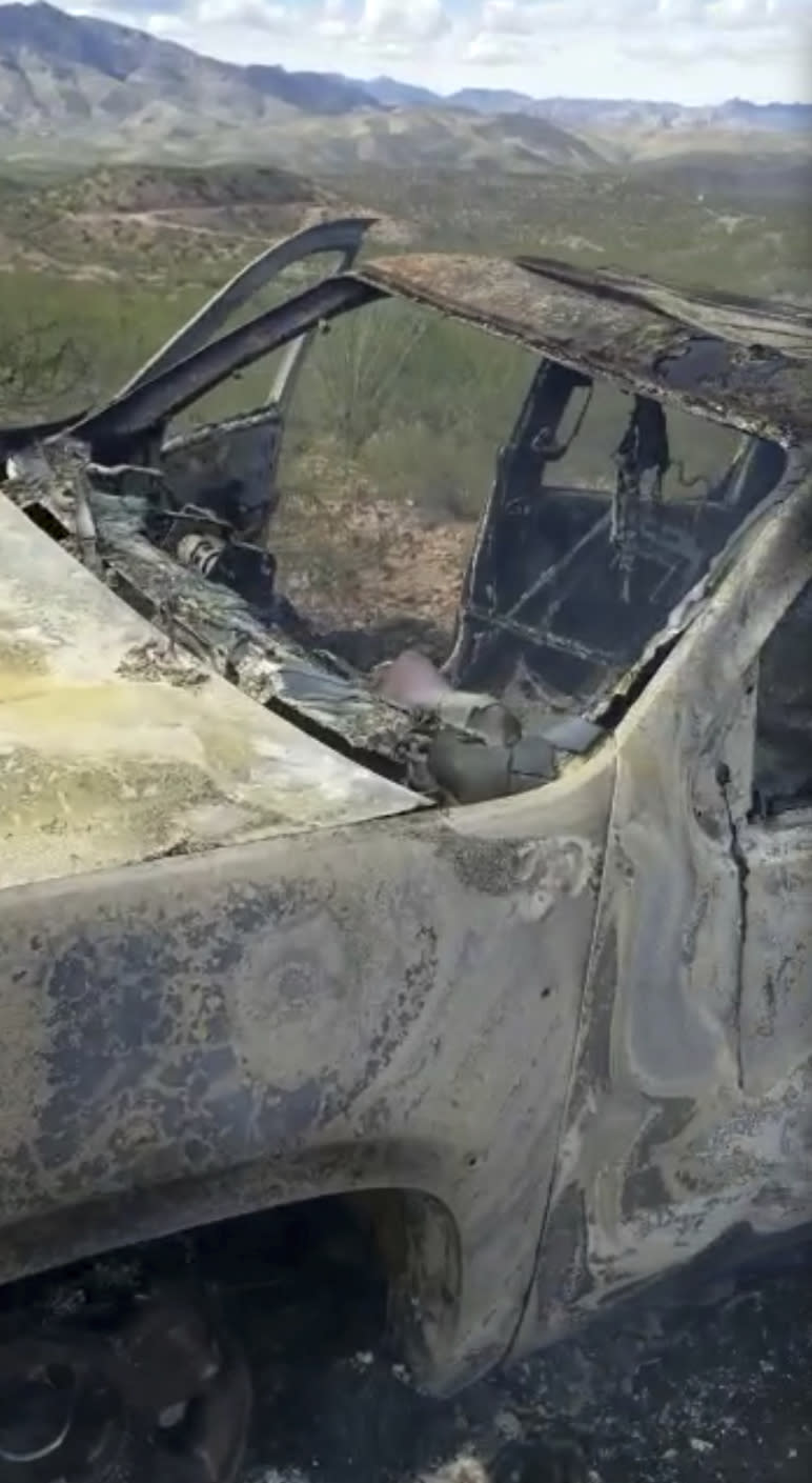 This frame from Nov. 4, 2019, video by Kenny Miller and posted on the Twitter account of Alex LeBaron shows a burned-out vehicle that was being used by some members of the LeBaron family as they were driving in a convoy near the Sonora-Chihuahua border in Mexico. Mexican authorities say drug cartel gunmen ambushed multiple vehicles, including this one, slaughtering several women and children. (Kenny Miller/Courtesy of Alex LeBaron via AP)