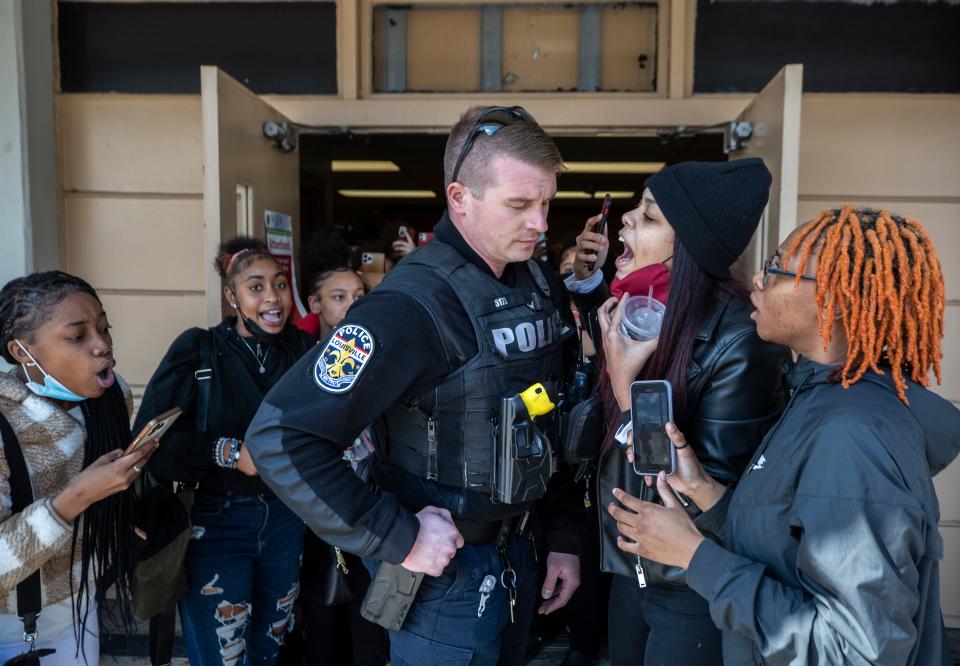 Louisville Metro Police officer Aaron Ambers is confronted by parents and students as he leaves Central High School. The police arrived to investigate a protest at the school over sexual assaults but found they were not welcome there. March 9, 2022