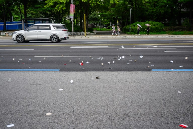 Piezas de envoltorios de alimentos lanzados por Corea del Norte en globos cargados de basura cubren el asfalto en Seúl el 24 de julio de 2024 (Anthony Wallace)