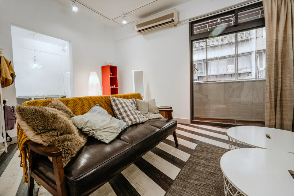 Interior of living room with sofa and cushions by wooden tables on rug