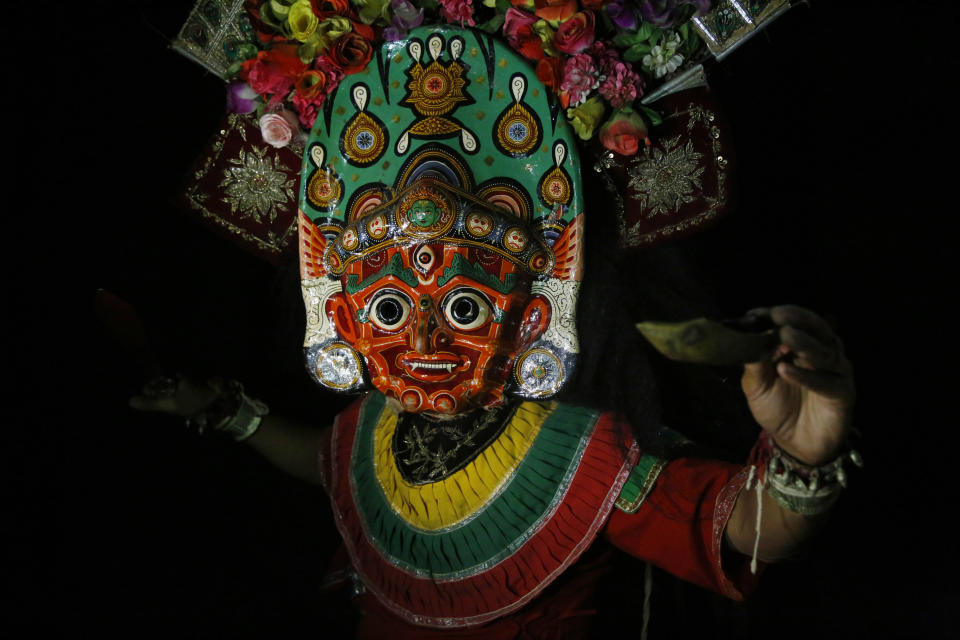 In this Sept. 23, 2018, photo, a dancer poses for photographs wearing mask of goddess Mahakali in Kathmandu, Nepal. For centuries, Nepal has celebrated the Indra Jatra festival of masked dancers, which officially begins the month-long festivities in the Hindu-dominated Himalyan nation. The dancers, who come from a variety of backgrounds, pull off this performance every year despite minimal financial support from the government and other sources, they say. (AP Photo/Niranjan Shrestha)