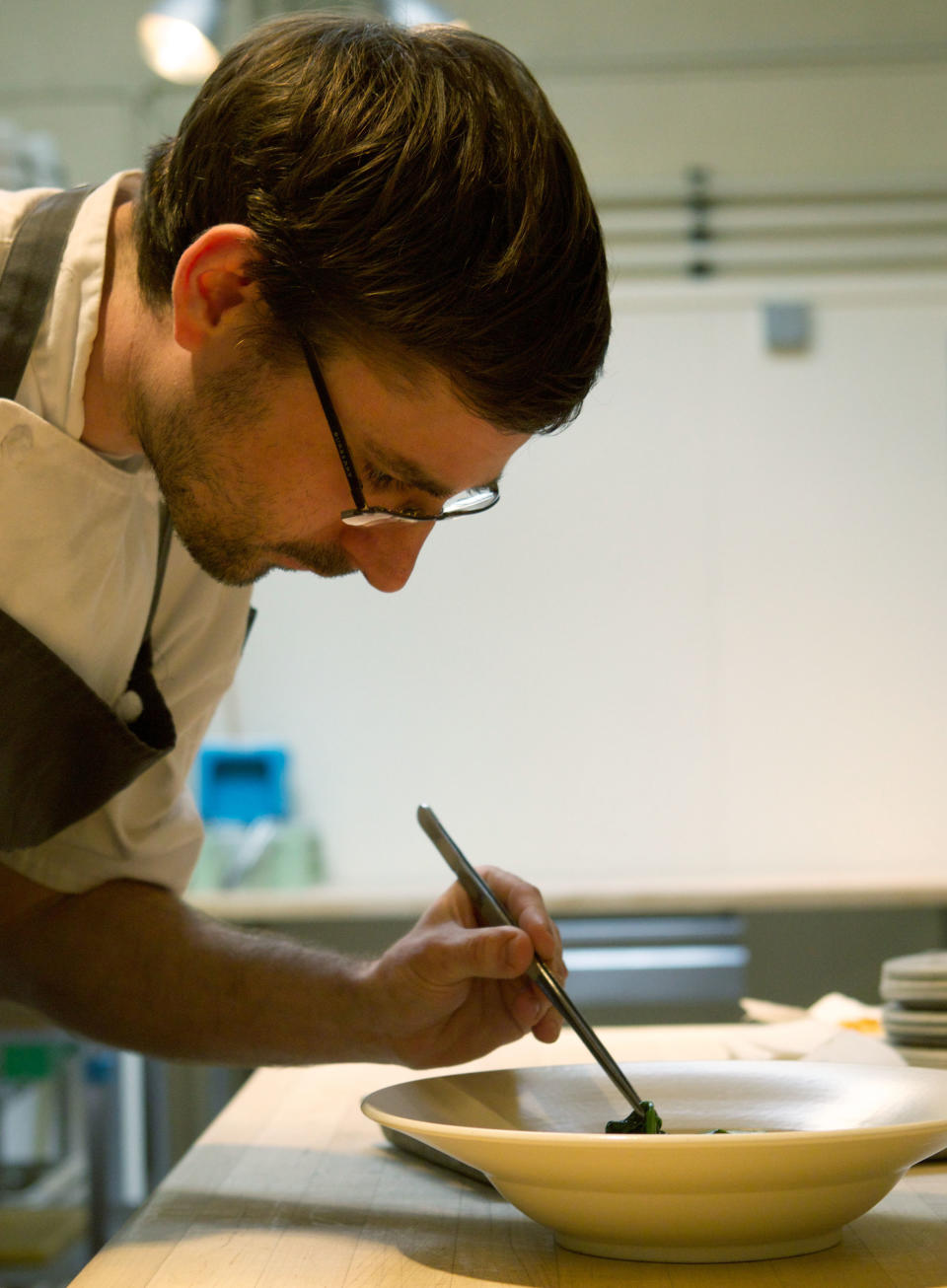 In this April 17, 2013 photo, Chef Justin Woodward prepares a grilled halibut with spring botanicals and brown butter fumet dish at the restaurant Castagna in Portland, Ore. "We're kind of the Wild West," he says. "We don't have a Michelin Guide. We don't have The New York Times breathing down our neck. We can basically do whatever we want." (AP Photo/The Oregonian, Doug Beghtel)