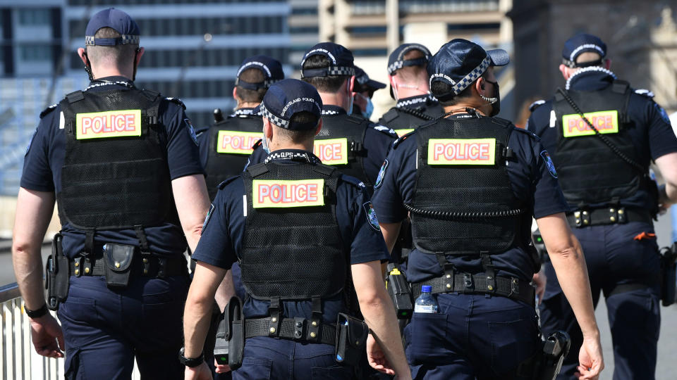 A group of Queensland Police officers are seen walking across the Victoria Bridge in Brisbane, Friday, October 15, 2021. (AAP Image/Darren England) NO ARCHIVING