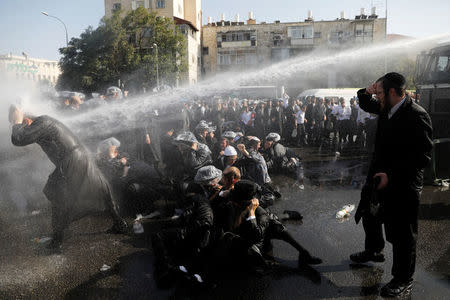 Israeli ultra-Orthodox Jewish men are sprayed with water during clashes with police at a protest against the detention of a member of their community who refuses to serve in the Israeli army, in Jerusalem September 17, 2017 REUTERS/Ronen Zvulun