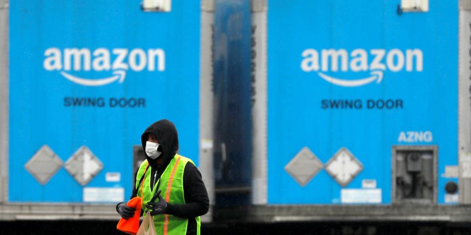 FILE PHOTO: A worker in a face mask walks by trucks parked at an Amazon facility as the global coronavirus outbreak continued in Bethpage on Long Island in New York, U.S., March 17, 2020. REUTERS/Andrew Kelly/File Photo