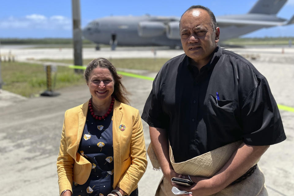 In this photo provided by the Australian Defence Force the Prime Minister of Tonga, Siaosi Sovaleni, right, joins the Australian High Commissioner to Tonga, Rachael Moore, to watch the arrival of the first Royal Australian Air Force C-17A Globemaster III aircraft at Fua'amotu International Airport near Nukuʻalofa, Tonga, Thursday, Jan. 20, 2022. The first flights carrying fresh water and other aid to Tonga were finally able to land after the Pacific nation's main airport runway was cleared of ash left by a huge volcanic eruption. (Australian Defence Force via AP)