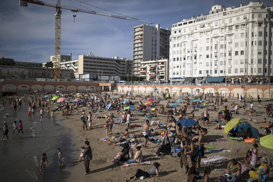 FILE - In this July 25, 2020, file photo, beachgoers enjoy the sun at the Plage des Catalans in Marseille, southern France. An outbreak among 18- to 25-year-olds at a seaside resort on the Brittany coast is crystallizing fears that the virus is flaring again in France, on the back of vacationers throwing COVID-19 caution to the summer winds. (AP Photo/Daniel Cole, File)