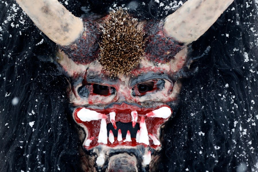 Reveler depicting devil poses for a photo during a traditional St Nicholas procession in the village of Valasska Polanka, Czech Republic, Saturday, Dec. 7, 2019. This pre-Christmas tradition has survived for centuries in a few villages in the eastern part of the country. The whole group parades through village for the weekend, going from door to door. St.Nicholas presents the kids with sweets. The devils wearing home made masks of sheep skin and the white creatures representing death with scythes frighten them. (AP Photo/Petr David Josek)