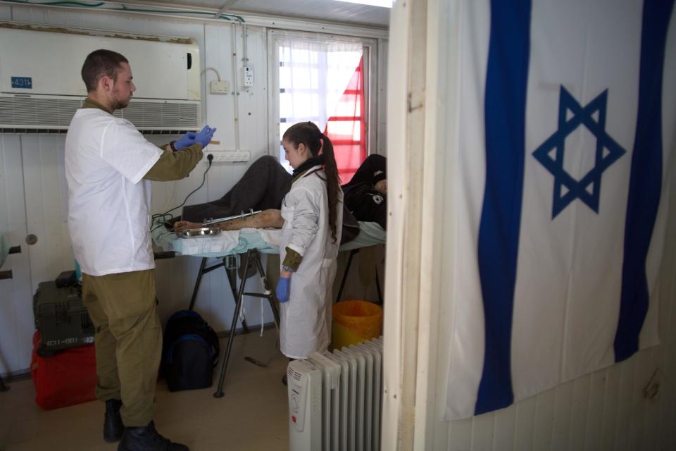 Members of the Israeli army medical staff tend to a Syrian man who was wounded in the ongoing violence in Syria, in a military hospital located in the Golan Heights near the border with Syria on Tuesday, Feb. 18, 2014. Since the Syrian conflict erupted almost three years ago hundreds of Syrians have received treatment in Israeli hospitals.(AP Photo/Menahem Kahana, Pool)