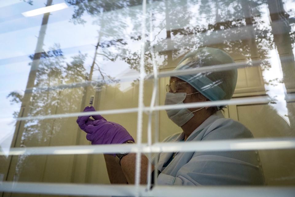 A medical worker preparing a shot of Russia's Sputnik V coronavirus vaccine is seen through a window of a local rural medical post in the village of Ikhala in Russia’s Karelia region, Tuesday, Feb. 16, 2021. Russia took pride in being the first country to approve a coronavirus vaccine, although it faced criticism from aboard for doing it before completing the advanced testing necessary to ensure Sputnik V’s safety and effectiveness. (AP Photo/Dmitri Lovetsky)