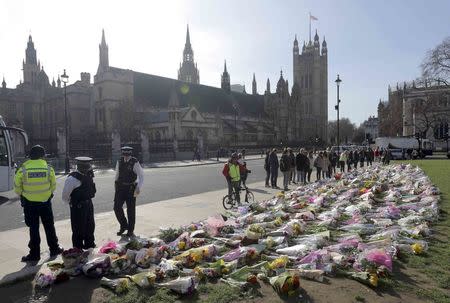 Police officers look at floral tributes in Parliament Square, following the attack in Westminster earlier in the week, in London, Britain March 25, 2017. REUTERS/Paul Hackett