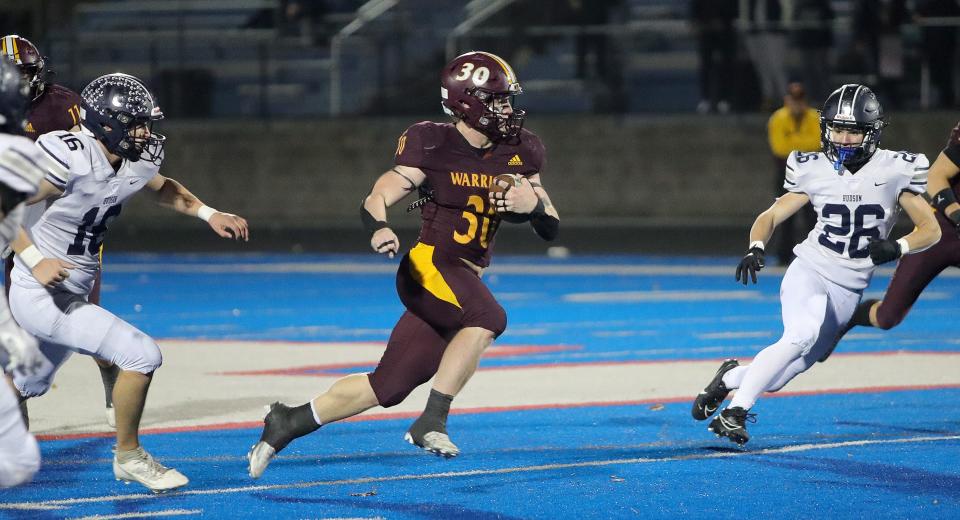 Walsh Jesuit's Brock Sherman (30) runs between Hudson defenders Nathan Judy, left, and Brennan Funyak during a regional semifinal Friday in Ravenna.